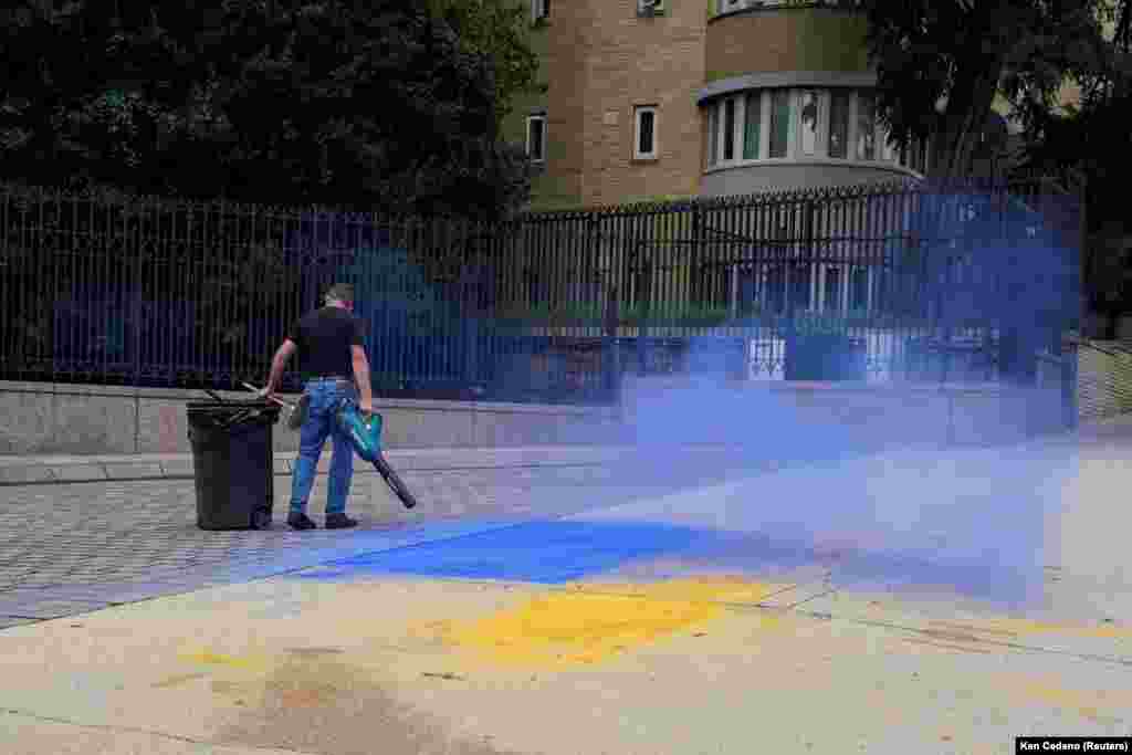 مردی در حال تمیز کردن بقایای پرچم اوکراین بر روی پیاده‌روی بیرون از سفارت روسیه در واشینگتن دی‌سی در اوت ۲۰۲۵.