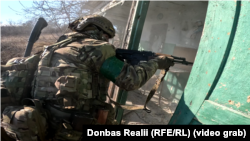 Розвідник 15-ої бригади НГУ «Кара-Даг» перевіряє будинок, де можуть бути російські солдати