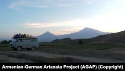 2019 թվականի պեղումների համար անհրաժեշտ սարքավորումներով բեռնված ֆուրգոնը: Հետին պլանում Արարատ լեռն է և Խոր Վիրապի վանքը։