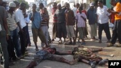 Жители сомалийского города Могадишо стоят возле тел двух погибших горожан. Иллюстративное фото.       