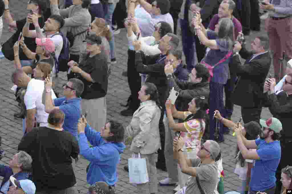 Ljudi posmatraju kako se crni dim vije iz dimnjaka Sikstinske kapele, 8. maja 2025. Dim nastaje spaljivanjem glasačkih listića poslije tajnog glasanja, a boja dima zavisi od vrste hemikalije kojom su posuti.