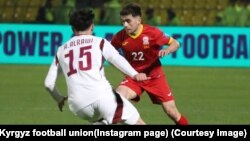 Кыргызстан менен Катардын футболчуларынын мелдеши. Алимардон Шүкүров (22) менен Ахмед ал-Рави (15) топ талашууда