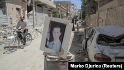 مردی با دوچرخه در حال عبور از یک پست بازرسی در دوما در حومه دمشق