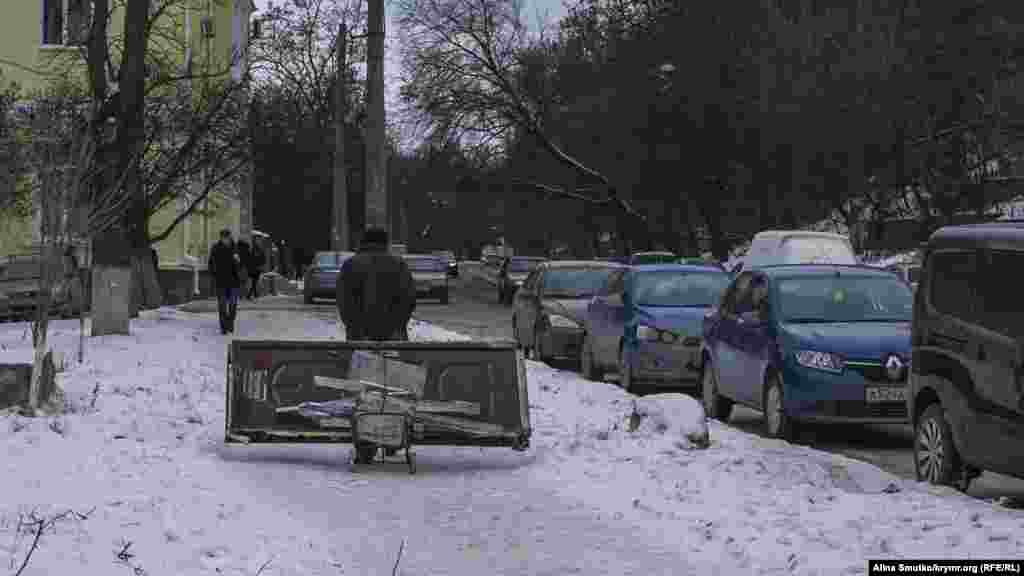 Мужчина тянет дверь на металлолом по заснеженным улицам Симферополя, 12 декабря 2016 года