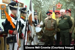 Выхаванцы «Грэнады» у форме Расейскай імпэрыі на выставе «Вайсковая атрыбутыка» ў Слонімскім краязнаўчым музэі. Разам зь імі Віктар Пенза і вайсковы пэнсіянэр Міхаіл Харчанка. На сьцяне шаўроны расейскай арміі зь літарай Z, дзеці трымаюць расейскі чорна-жоўта-белы імпэрскі сьцяг.