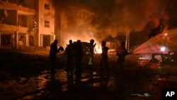 Израильдің солтүстігіндегі Хайфа қаласында Иран зымыраны түскен жерде өрт сөндіріп жүрген адамдар. 15 маусым, 2025 жыл.