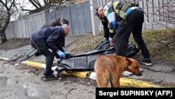 Буча көшесінде қаза тапқан кісіні арнаулы қапқа салып жатқан адамдар. Украина, 3 сәуір 2022 жыл.