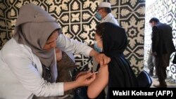 A health worker (left) inoculates a woman with vaccine against COVID-19 at a vaccination center in Kabul in April.
