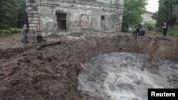 Слідчі працюють біля воронки на місці одніє із будівель у Харкові, куди прилетіла російська ракета. 27 квітня 2024 року