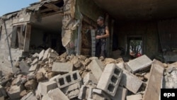 Чоловік біля знищеного обстрілом будинку в Сартані поблизу Маріуполя, серпень 2015 року