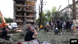 Рятувальники відпочивають під час роботи біля житлових будинків і дитячого садка, зруйнованих ракетним ударом у Києві, 8 липня 2024 року