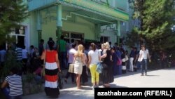 Aşgabatda, Türkmenistanyň döwlet ulaglar we aragatnaşyk institutynyň köne binasynyň okuw korpuslarynyň biriniň öňünde sanawa durmak üçin duran ýaşlar