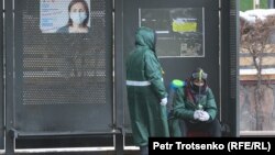 Занимающиеся дезинфекцией общественных мест рабочие на автобусной остановке в Алматы. 28 февраля 2021 года.