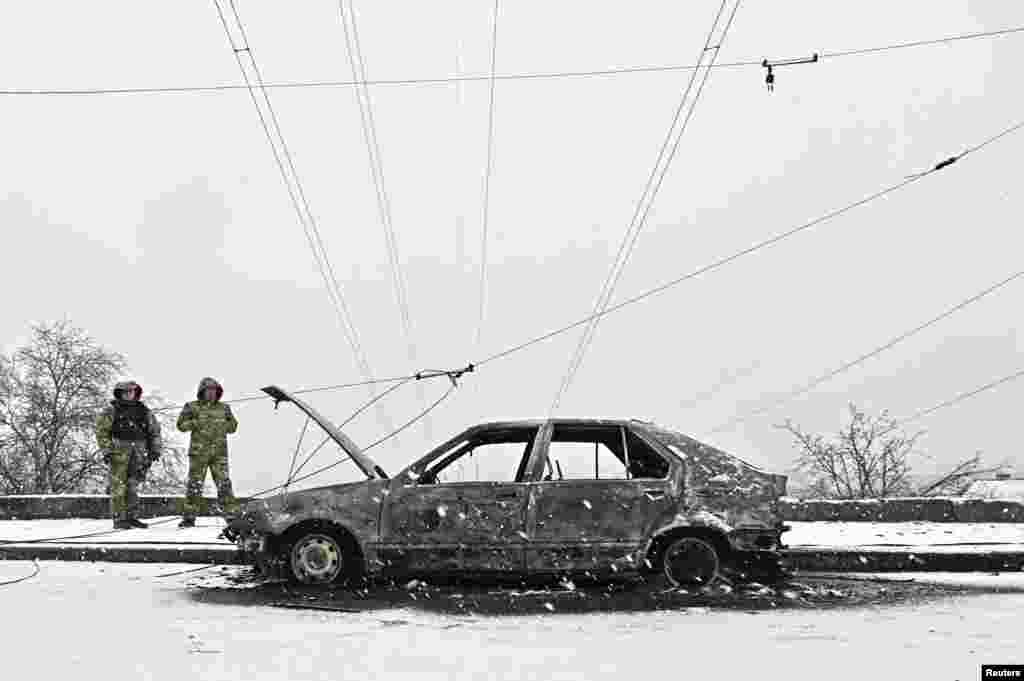 Investigators stand next to a car destroyed by a Russian missile strike in the southeastern city of Zaporizhzhya.