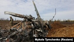 Український військовослужбовець біля залишків знищеного російського гелікоптера Мі-8 на Київщині, 27 квітня 2022 року
