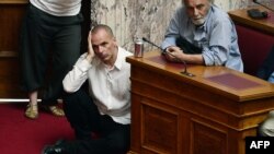 یانیس واروفاکیس (نشسته روی زمین) وزیر دارایی یونان در حال گوش دادن به سخنرانی نخست‌وزیر