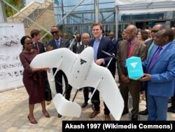 Германдык “Вингкоптер” аба мейкиндиги компаниясынын негиздөөчүлөрүнүн бири жана аткаруучу директору Том Плүммер (ортодо) Руанданын президенти Пол Кагаме (Плүммердин сол жагында), бул өлкөнүн маалымат, байланыш технологиясы жана саамалыктар министри Пола Ингабире айым (солдо биринчи) жана инфратүзүм министри Клавер Гатете (оңдо биринчи) менен “Wingcopter 178 HL” дронун жакындан көрүүдө. 07.2.2020.