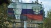 A view through a car window shows a board displaying a Russian state flag and an image of President Vladimir Putin in Stepanakert after exodus of ethnic Armenians from Nagorno-Karabakh, October 2, 2023.