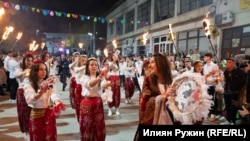 Площадът е пълен с хора, които танцуват.