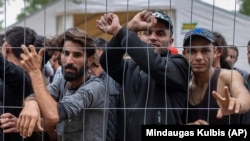 Migrants stand behind a fence inside a newly built refugee camp in Lithuania on August 4.