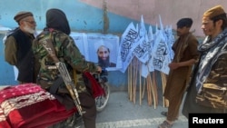 Taliban fighters in Kabul with posters of the militant group's supreme leader, Mullah Haibatullah Akhundzada, who announced dozens of new official appointments on October 4. (file photo) 