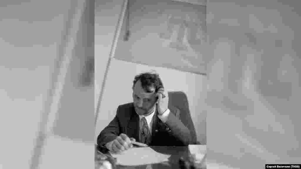 1994 senesi iyün ayı. O vaqıt Qırımtatar Milliy Meclisiniñ reisi olğan Mustafa Cemilev odasınıñ divarındaki bayraqnen