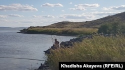 Атом көлінде балық аулап отырған адам.