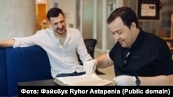 Рыгор Астапеня (зьлева) і Павел Мацукевіч з кнігай Сімяона Полацкага "Жазло кіраваньня".