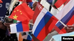 Spectators wave Russian, Chinese, and other flags during a June ceremony in central Moscow marking the 100-day countdown to the upcoming Intervision contest on September 20. 