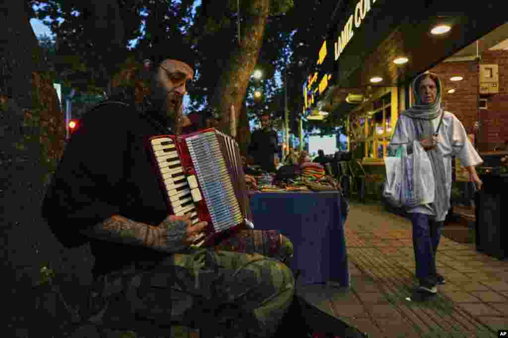 یک نوازندهٔ خیابانی در حال نواختن آکاردئون در پیاده‌رو خیابانی در شمال تهران