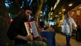 یک نوازندهٔ خیابانی در حال نواختن آکاردئون در پیاده‌رو خیابانی در شمال تهران
