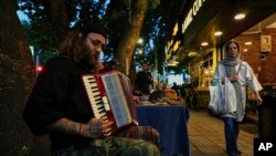 یک نوازندهٔ خیابانی در حال نواختن آکاردئون در پیاده‌رو خیابانی در شمال تهران