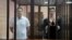 Maksim Znak (left) and Maryya Kalesnikava stand inside a defendants' cage as they attend a court hearing in Minsk on September 6.