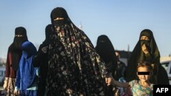 Бойцы поддерживаемых США курдских формирований сопровождают женщин и детей —  членов семей ИГ. Сирия, 2019 год.