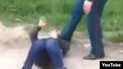 Сотрудник узбекской милиции пинает лежащую на земле пожилую женщину, архивное фото.