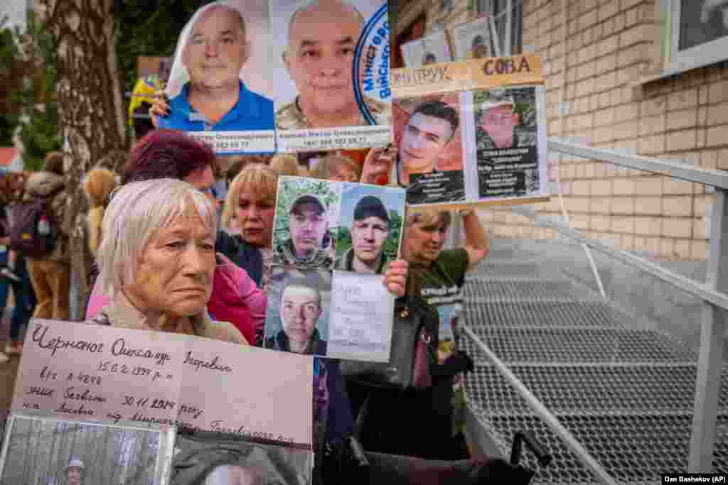 Рідні з фотографіями своїх зниклих безвісти близьких під час нового обміну полоненими між Росією та Україною в Чернігівській області, 19 червня 2025 року