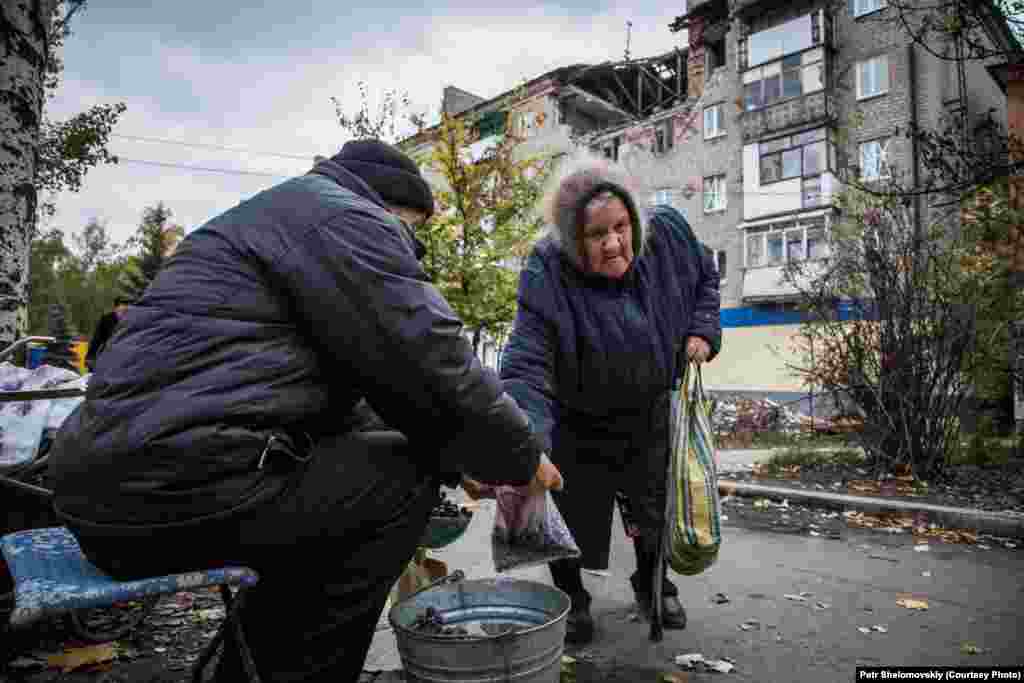 Nikolai&nbsp;sells grapes,&nbsp;grown&nbsp;in his own garden, to an elderly woman in front of a destroyed building in Gorlovka. According to the new separatist mayor, 80 percent&nbsp;of the city&#39;s population has returned to their homes. Job opportunities are still very limited 