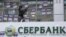 Активіст цивільного корпусу «Азов» клеїть наліпку на вікно центрального відділення «Сбербанку». Київ, лютий 2017 року