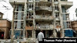 Жител на Киев гледа жилищна сграда, пострадала от удар на руски дрон в хода на руската атака срещу Украйна, 25 май 2025 г.