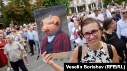 Жена държи плакат с колаж между прасе и тиква, София, 22 юли.