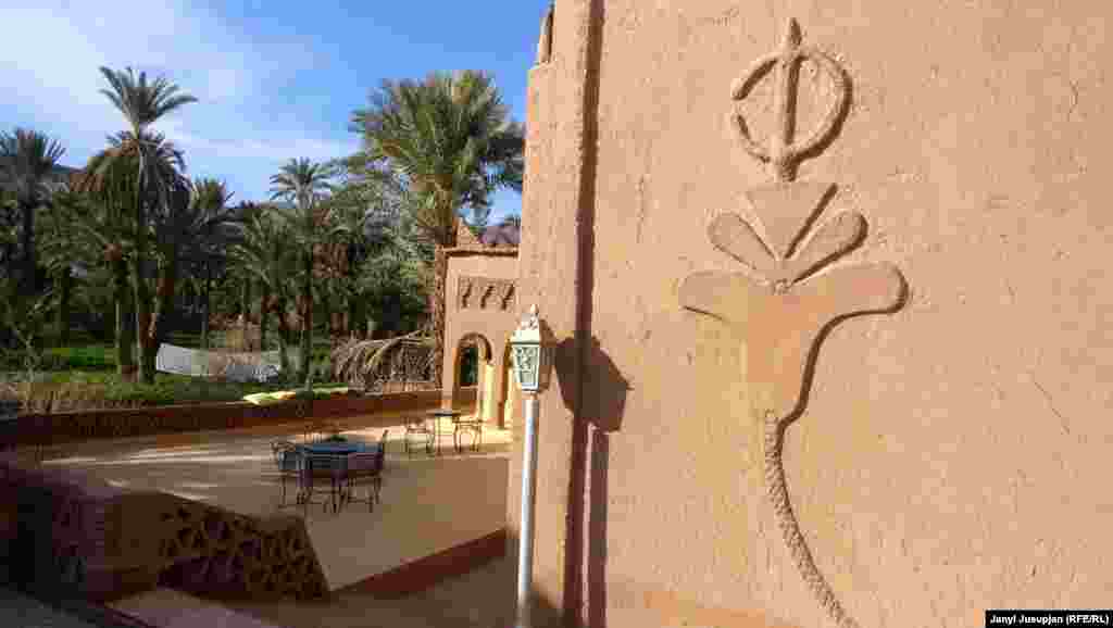 Элемент берберской графики на стене гостиницы Итрам. Итрам на самом деле большой комплекс, состоящий из двух зданий для гостей, отдельной приемной с Wi-Fi, кухней, бассейном и просторной чайханой с видом на пальмовый сад. Здания построены из глины, окна из разноцветныx стекол, везде ковры и подушки. Проживание с завтраком, а вне сезона и с ужином, стоит 30 евро на человека, но если вы остаетесь на больший срок, то можно договориться и дешевле.