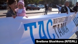 Женщина с ребенком на руках на площади перед акиматом Астаны держит растяжку: "Тасмағамбетов, тастама" (Тасмагамбетов, не выгоняй).  Астана, 25 сентября 2012 года.