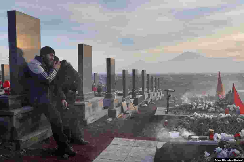 Men mourn a loved one at Yerablur cemetery on December 19.&nbsp;