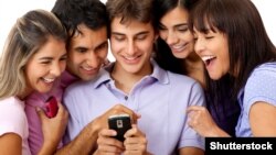 Birnäçe ýaş oglan-gyzlaryň mobil telefonda gyzykly waka tomaşa edip duran pursatyny görkezýän surat.