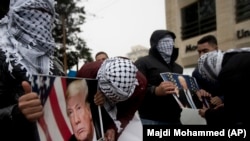 Палестинські активісти в Рамаллі, прикривши обличчя, тримають зображення Дональда Трампа, 6 грудня 2017 року