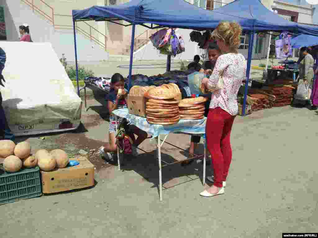 Lebap welaýatyndaky bazarlaryň birinde gyzjagaz bir ýandan nahar iýýär, bir ýandan hem çörek satýar.