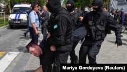 Полицейский спецназ тащит задержанного во время несанкционированной акции в Алматы с требованием «освободить политических заключенных». 10 мая 2018 года.