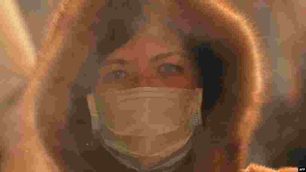 Жінка у масці проходить крізь пару, що піднімається від вареної кукурудзи в Москві