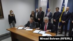 Political leaders Bakir Izetbegovic (left) and Dragan Covic sign the agreement in Mostar on June 17. 
