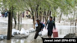 Afghan men carry their belongings as they evacuate from their residential area after flash flooding in the west of Kabul on April 16. 